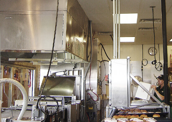 Cleaning equipment beneath stainless steel extraction hoods in a commercial kitchen